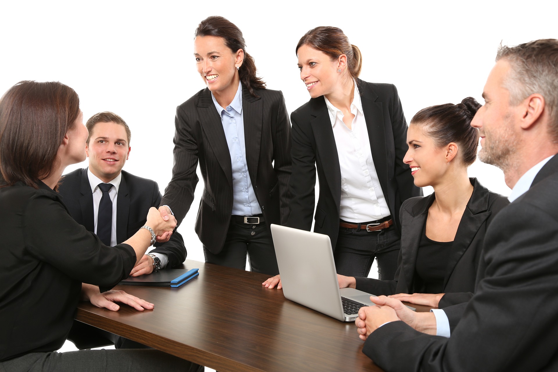 Six business professionals sitting and standing around a desk.