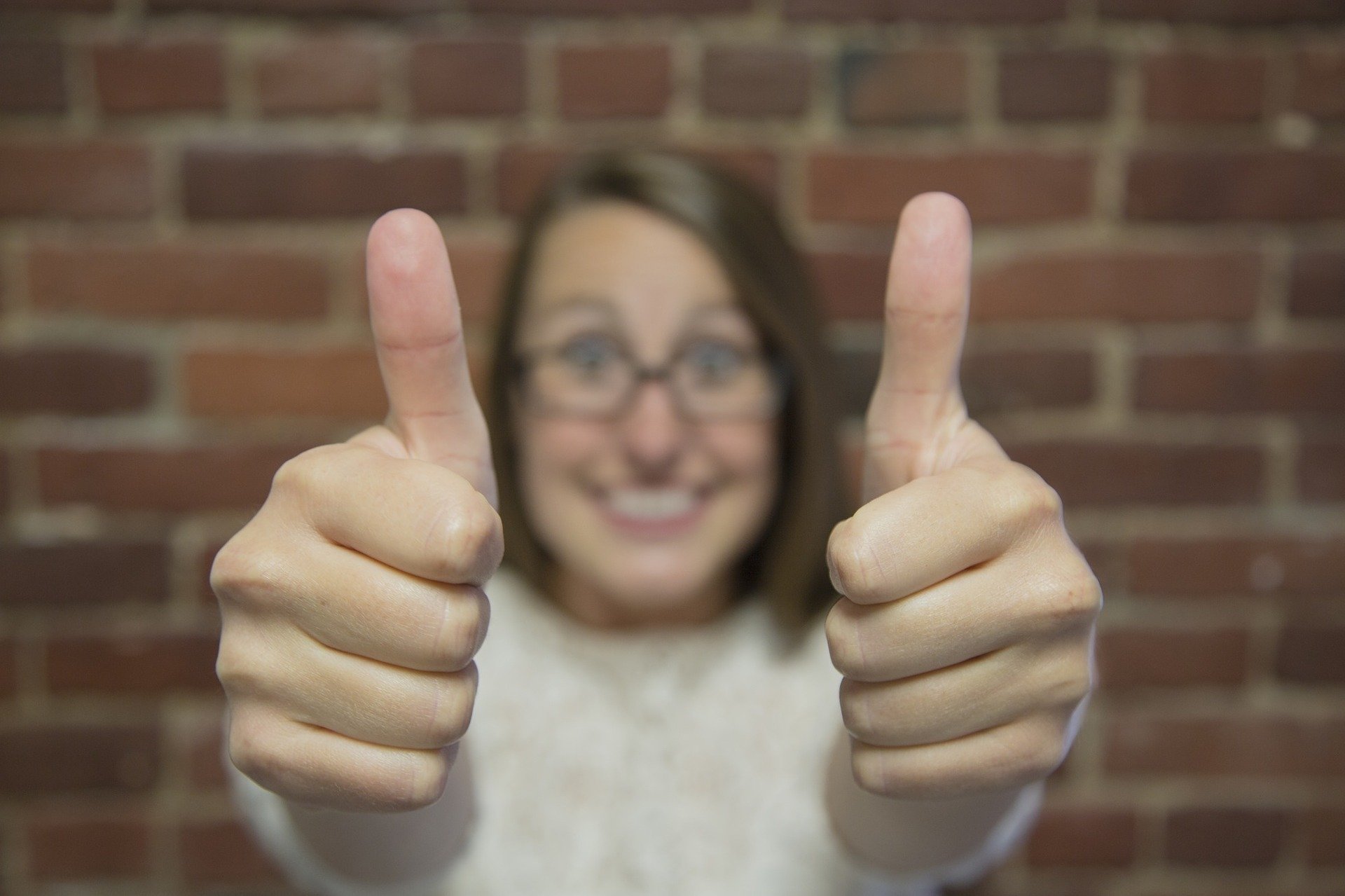 Blurred image of a person holding up two thumbs ups