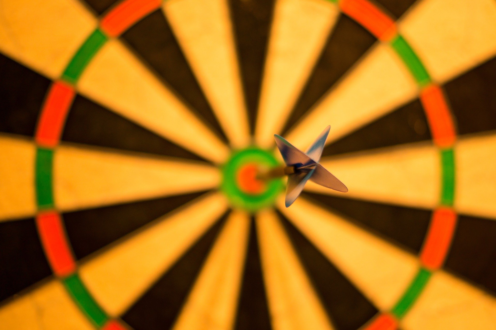 Blurry dart board image with a dart in the bullseye