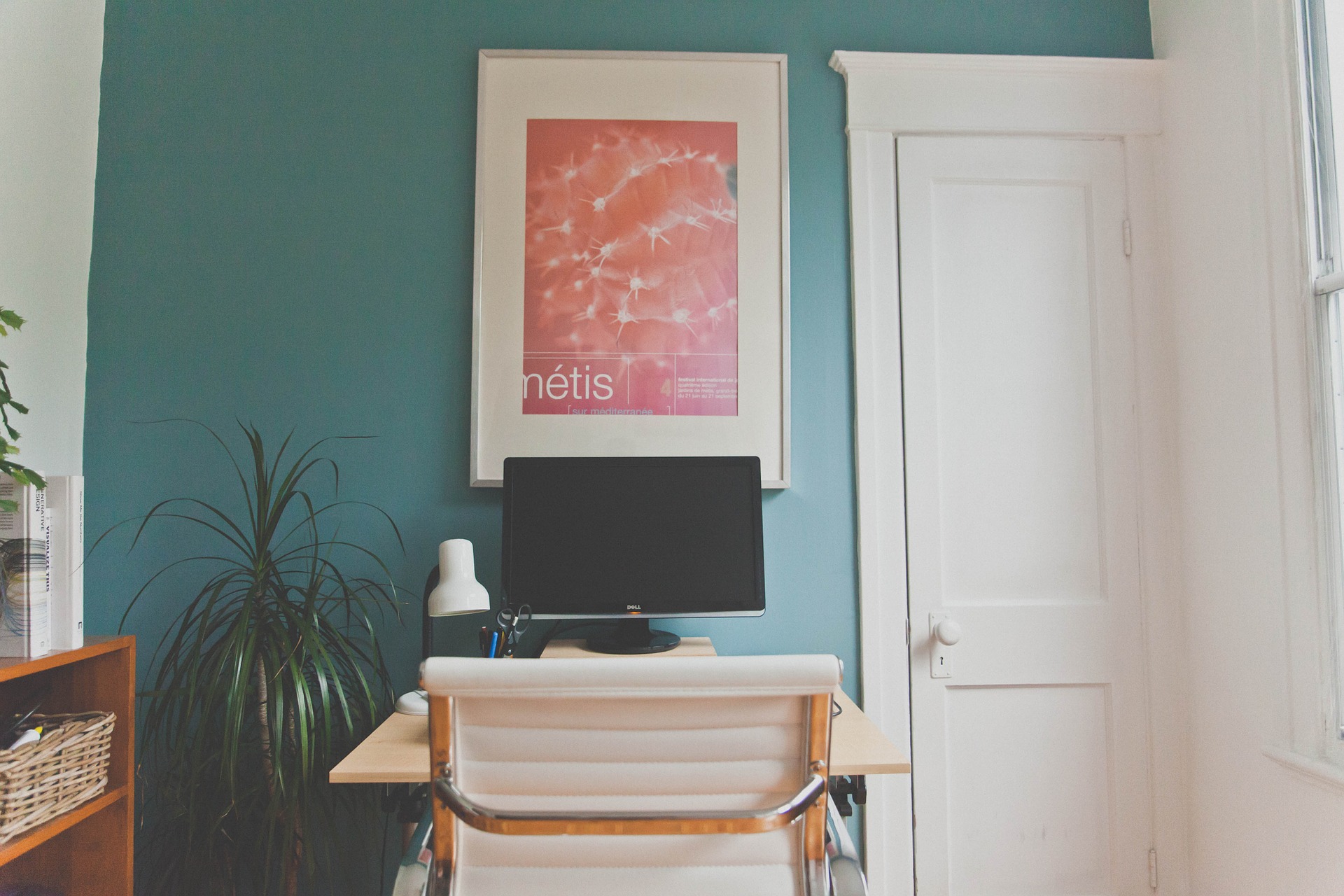 Small room with blue walls, a white desk and a blank computer screen