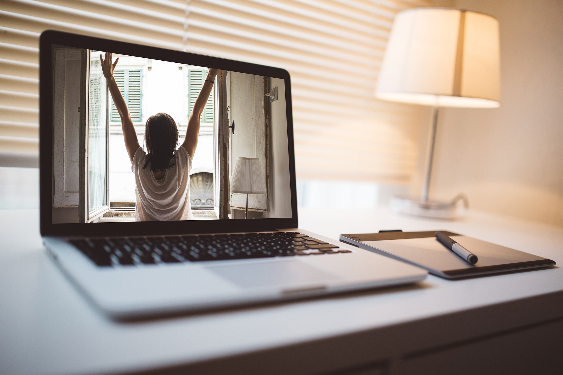 An open laptop sitting on a desk with a person stretching on the screen