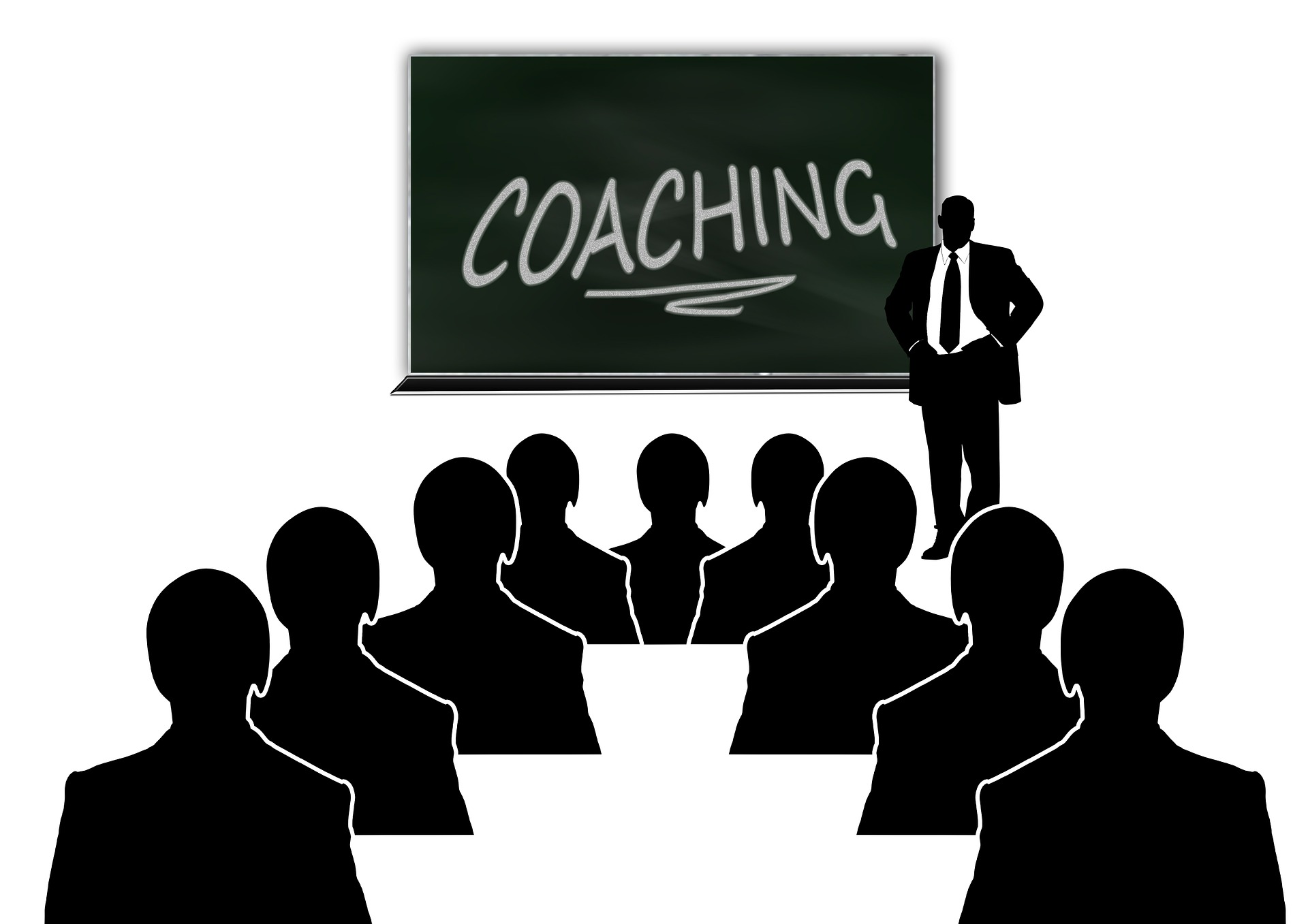 A person standing in front of a blackboard with "Coaching" written on it presenting to a group.