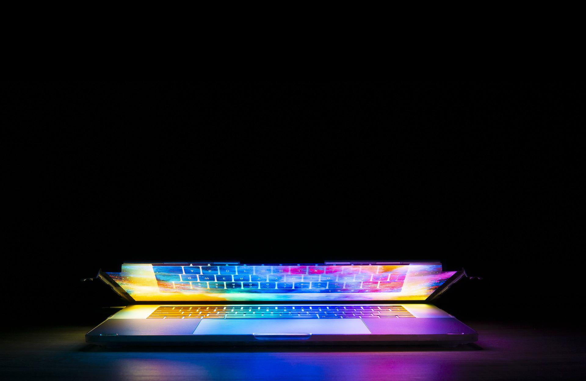 A partially closed laptop with a screen glowing different colors.