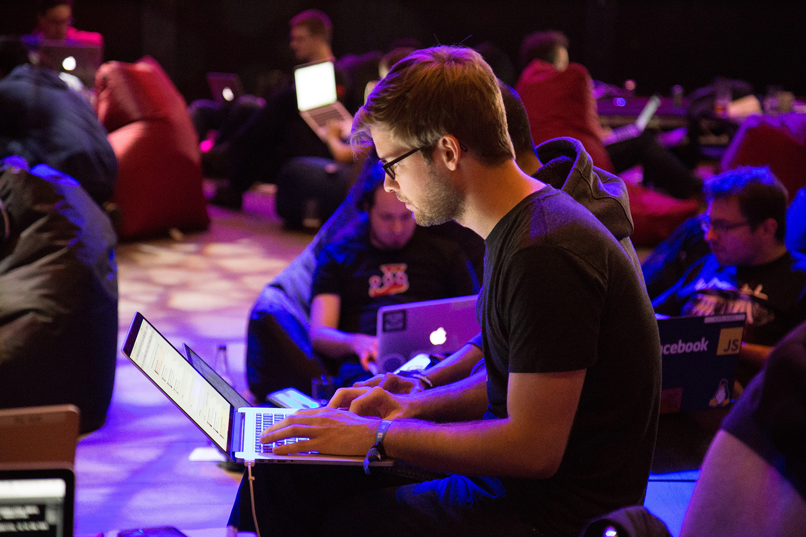 A man looks at his laptop among a crowd of people also looking at their laptops.