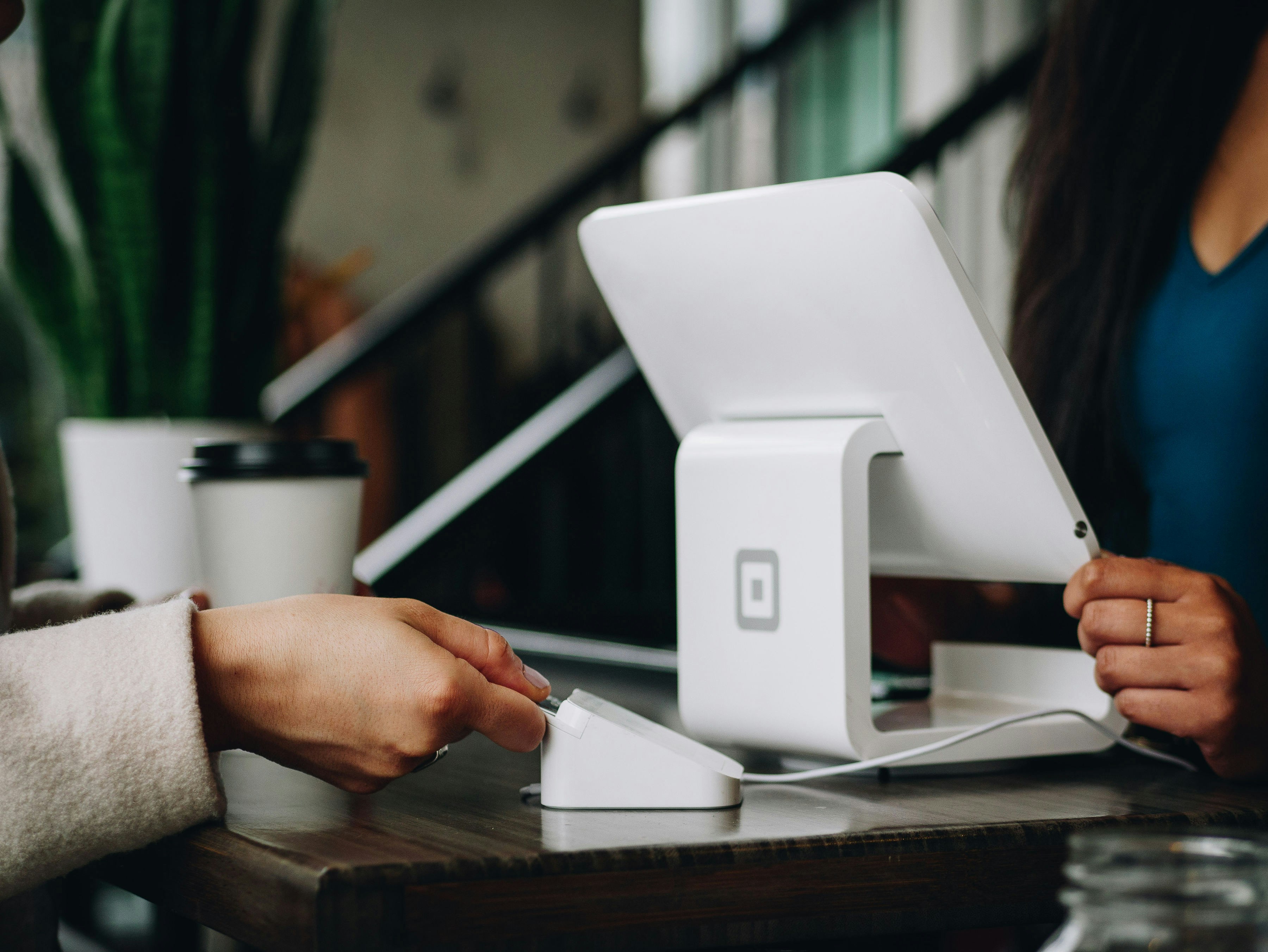 A person inserts their debit card as another person looks at a computer screen across the counter.