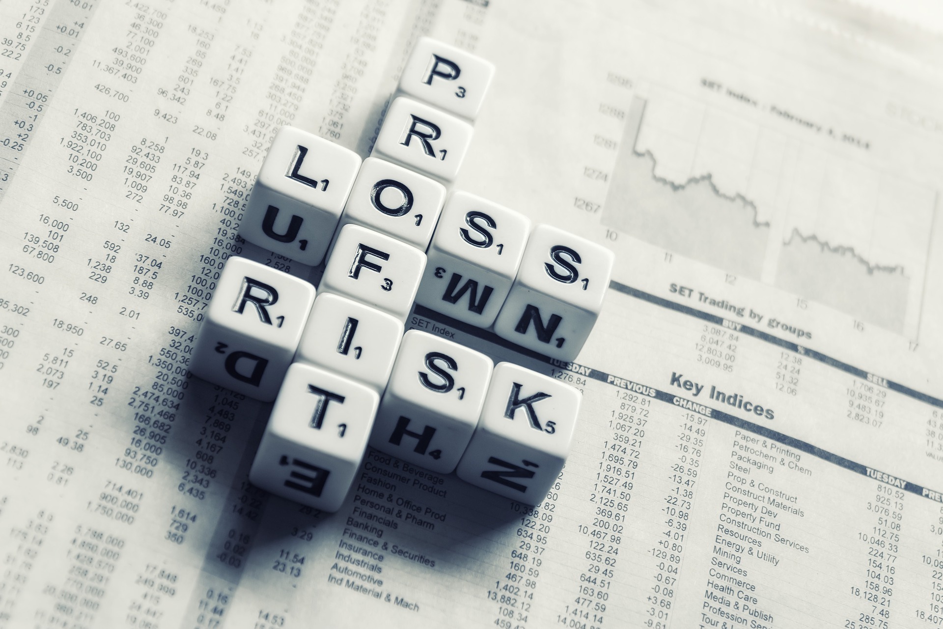 Lettered dices making a crossword on a newspaper.