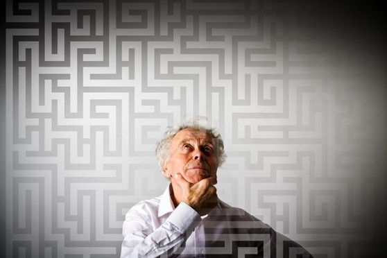 Man_thinking An older man looks up with his finger and thumb on his chin.
