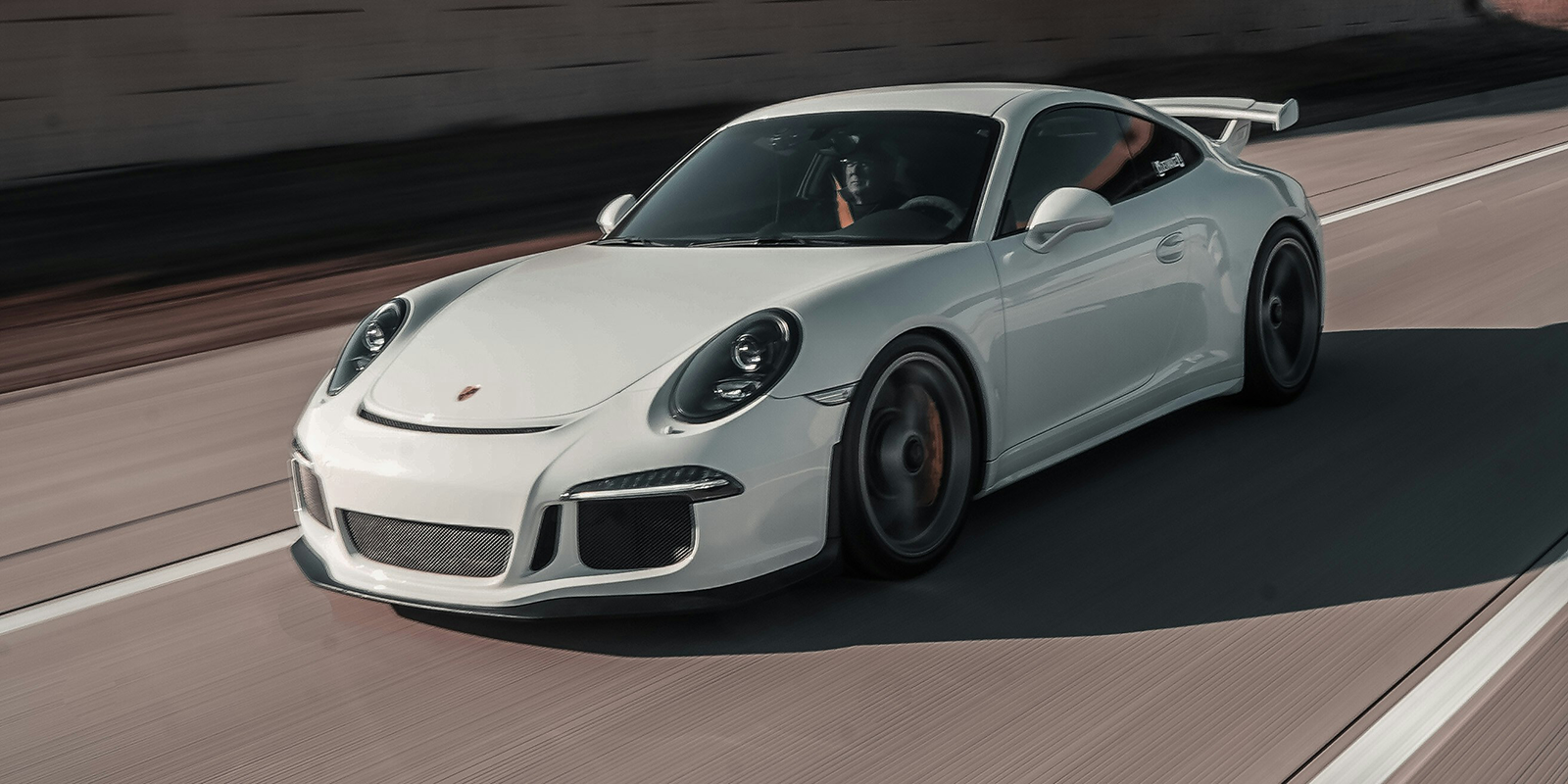 A white Porsche drives down a highway.
