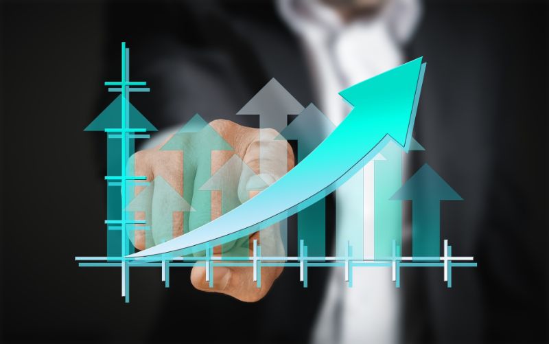 A hand pointing at a rising sales growth chart